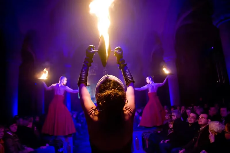 Artistes tenant des torches et un grand feu vertical devant le public pendant le spectacle Variations sur la flamme.