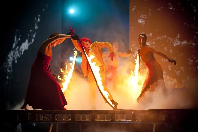 Deux artistes agitant de grands tissus rouges et noirs autour de flammes au sol pendant Variations sur la flamme.