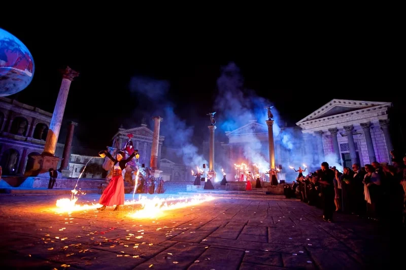 Artistes en train de faire couler du feu devant un monument antique