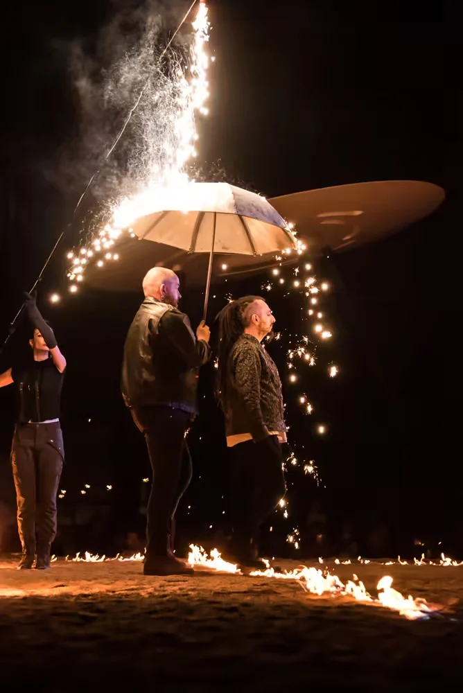 Groupe d’artistes autour d’une grande structure blanche, avec gerbes d’étincelles et cercle de feu au sol pendant Horizons.
