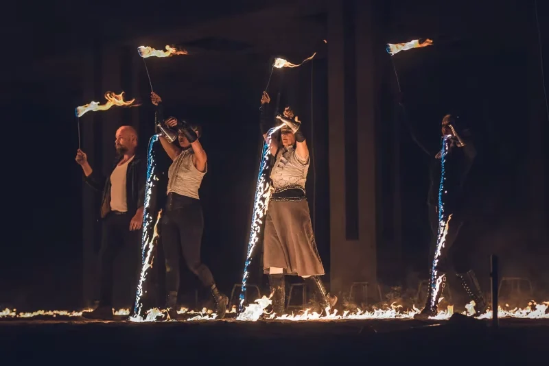 Quatre artistes traversant une ligne de feu liquide avec des torches enflammées dans une scène chorégraphiée d’Horizons.