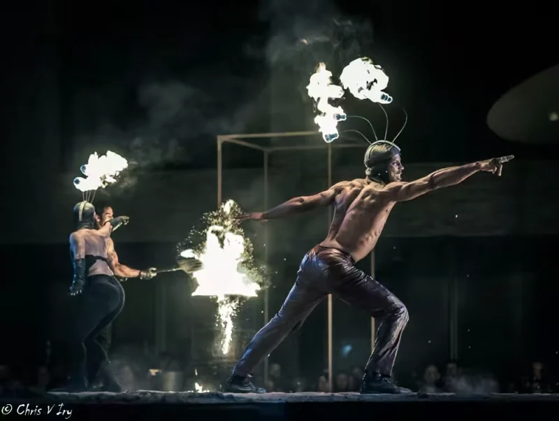 Trois artistes manipulant le feu autour d’un danseur en extension, dans une scène chorégraphiée du spectacle Mirador.