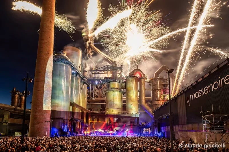 Feux d’artifice au-dessus d’un site industriel illuminé pendant le spectacle Y’a d’la joie.