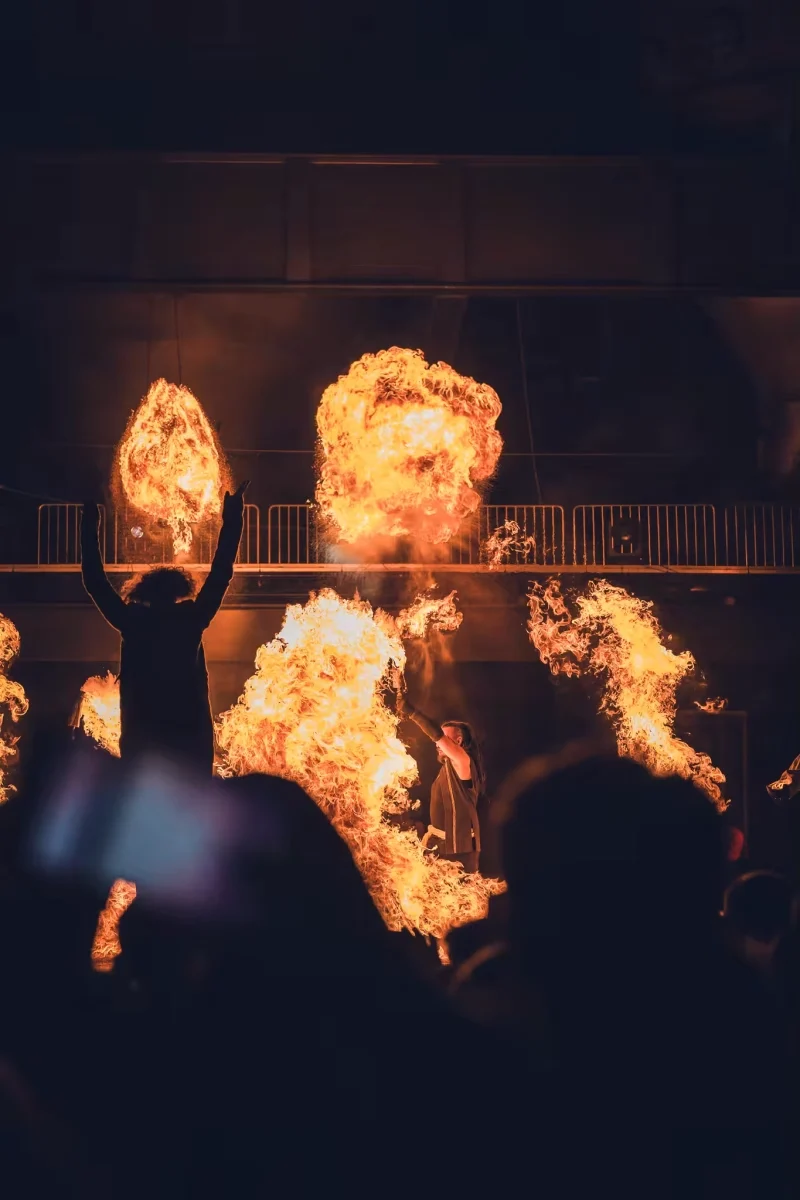 Grande flamme projetée au centre de la scène, entourée d’artistes dans le spectacle Y’a d’la joie.