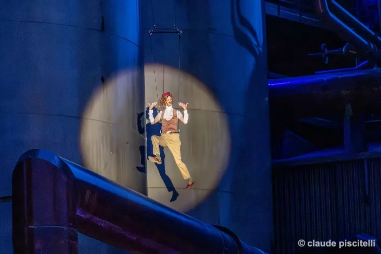 Artiste aérien suspendue dans les airs pendant une scène nocturne de Y’a d’la joie.