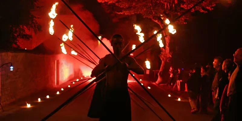 Groupe d’artistes de feu dans une mise en scène nocturne du spectacle Passage