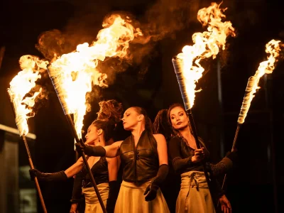 Trois artistes du spectacle Eden tenant des torches enflammées dans une scène nocturne spectaculaire.