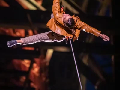 Artiste acrobate suspendue à une corde dans une structure métallique pendant le spectacle Merveilles.