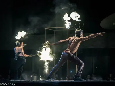 Trois artistes manipulant le feu autour d’un danseur en extension, dans une scène chorégraphiée du spectacle Mirador.