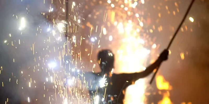 Artiste de feu tenant une lance enflammée au milieu d’effets pyrotechniques dans Peplum